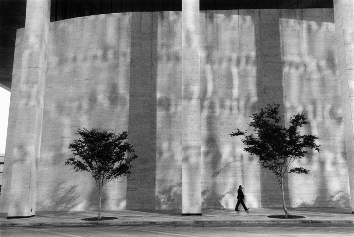 Man walking in front of building Houston, undated