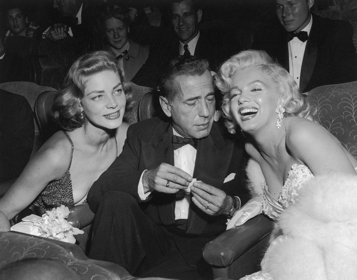 1953:  EXCLUSIVE Married American actors Lauren Bacall (L) and Humphrey Bogart (1899 - 1957) pose with American actor Marilyn Monroe (1926 - 1962) at the premiere of director Jean Negulesco's film, 'How to Marry a Millionaire'. Bacall and Monroe costarred in the film.  (Photo by Darlene Hammond/Hulton Archive/Getty Images)